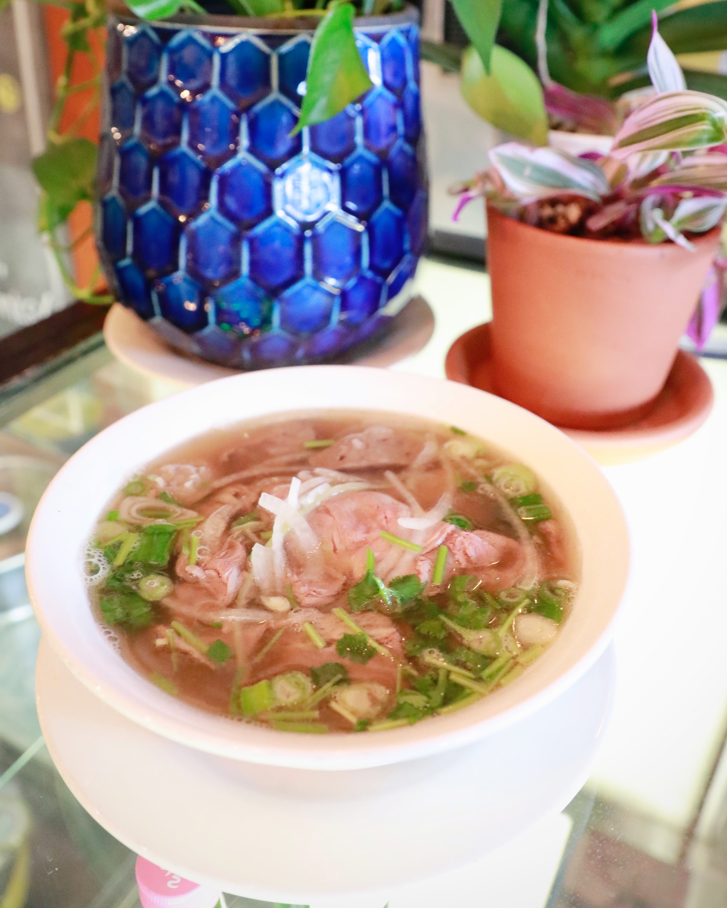Steaming bowl of Vietnamese phở with fresh herbs at La Cà Bar